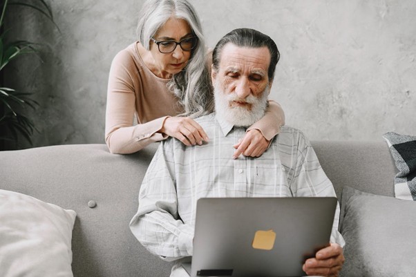 An elderly couple looking at a laptop.