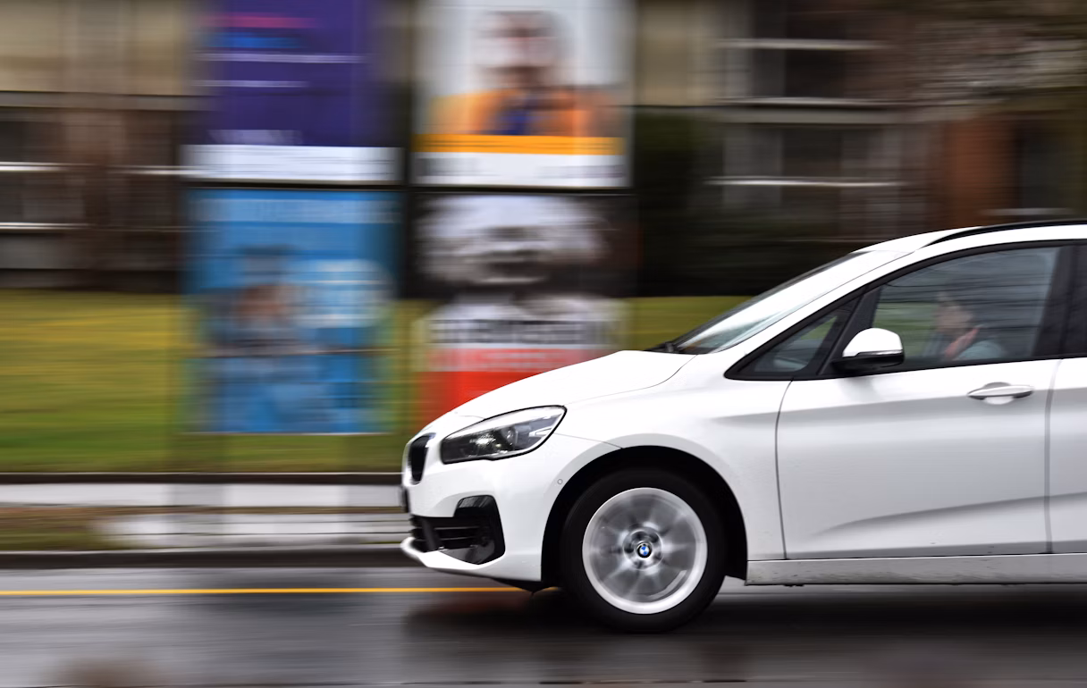 A white car overspeeding on the road during daytime
